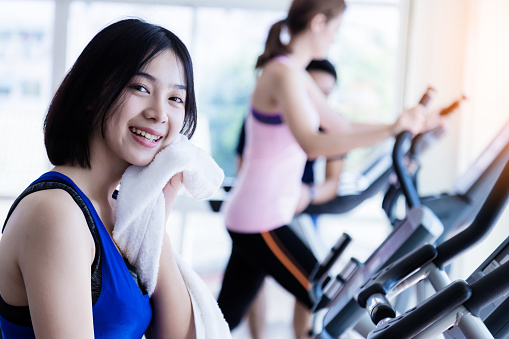 Young cute Asian girl relaxing after cadio workout in fitness health club