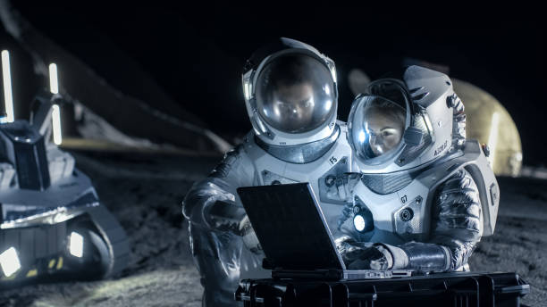 Two Astronauts Wearing Space Suits Work on a Laptop, Exploring Newly Discovered Planet, Send Communicating Signal to Earth.